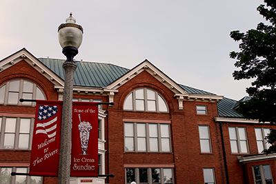 A historic brick building in Two Rivers with street banners